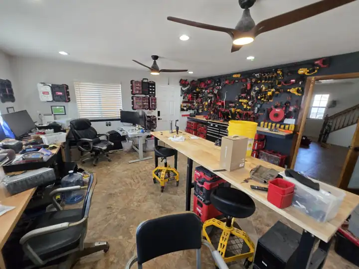 Office desks on one side, tool wall on the other